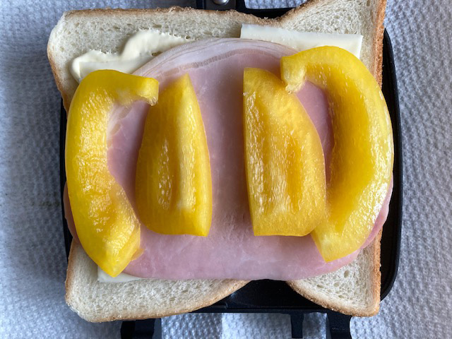 チーズ、ハム、パプリカをのせた。 この上にもう1枚、ハムをのせてはさんで焼いた。